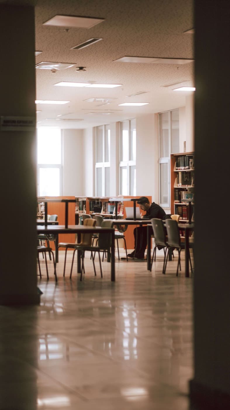 Computer lab with rows of monitors beside a wall of books