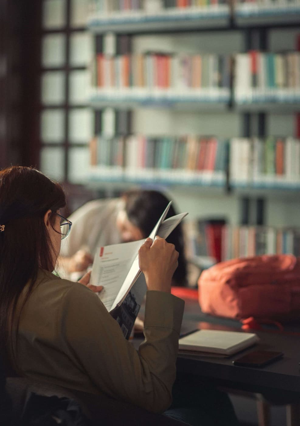 Student reading through printed documentation in a library